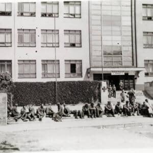 Ranění příslušníci Wehrmachtu před rezervní nemocnicí čekají na transport (květen 1945)
